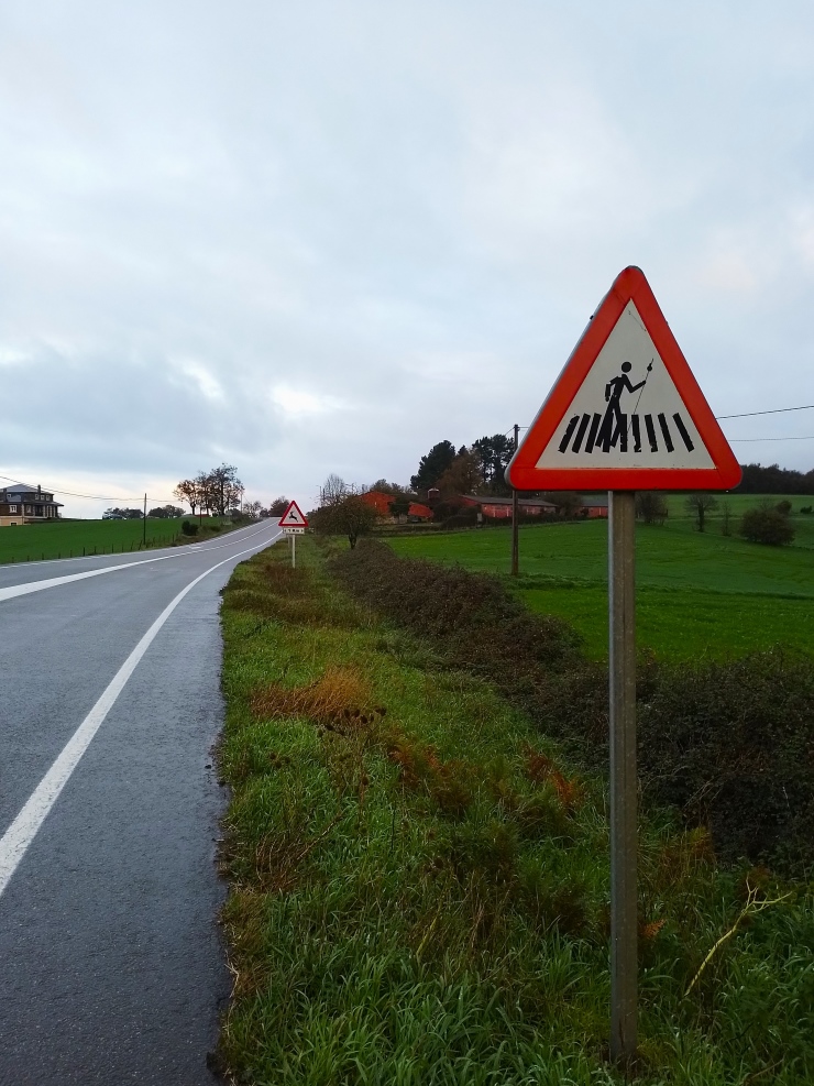 Autotien varressa liikennemerkki, jossa kuva pyhiinvaeltajasta Camino de Santiago pyhiinvaellusreitillä.