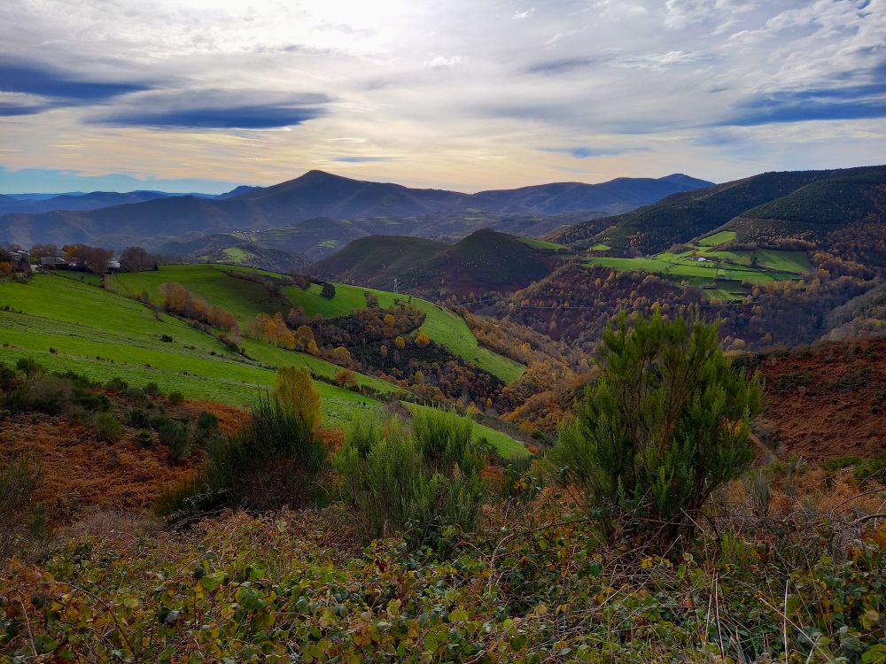 Vihreä vuoristonäkymä ja pilvinen taivas Camino de Santiagon pyhiinvaellusreitillä.