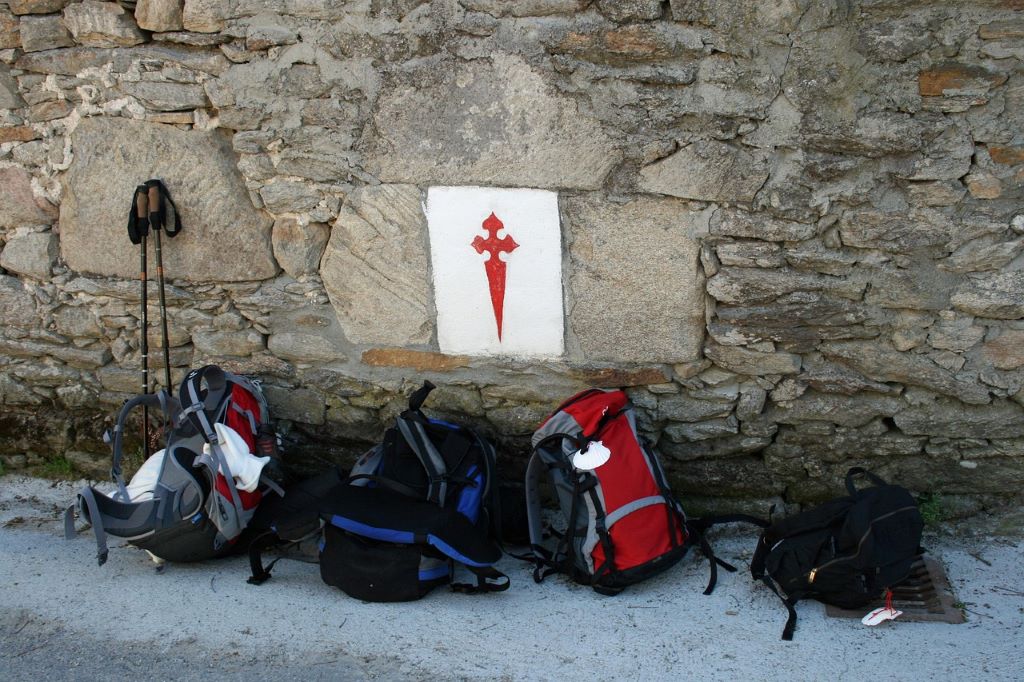 Reppuja nojaamassa kiviseinään Santiago de Compostelan pyhiinvaelluksella.